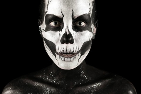 Isolated on black, closeup picture, beautiful young blonde caucasian woman with scull body art,