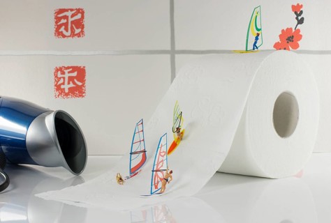Indoor surfing by little world miniatures on toilet paper with hairdryer as background for the wind