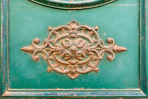 An image of a rusty ornamental decoration at a green door in Italy