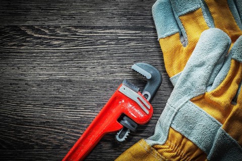 Plumbing adjustable wrench safety gloves on wooden board
