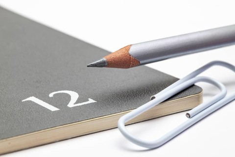Organizer for the month of December, silver pencil and white paperclip on the white table