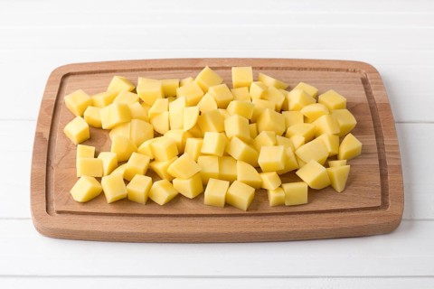 Food, Wooden board with fresh diced potatoes on a light gray background. Stage of cooking vegetable