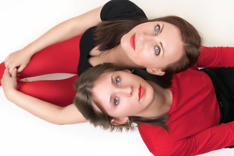 Top view of mom and daughter sitting with their backs to each other and put their heads on each