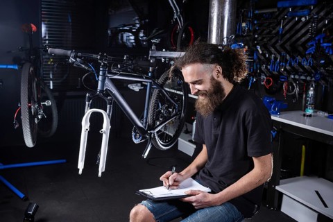 Bicycle Workshop Technician Doing Administrative Work. Bicycle mechanic writing in his checklist