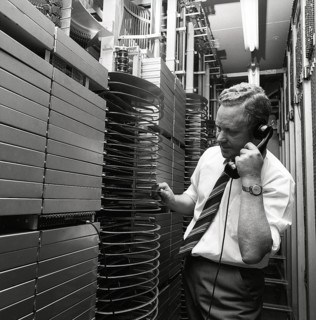 Telephony in the 1970s. A man in a room with an automatic switchboard connecting the calls through