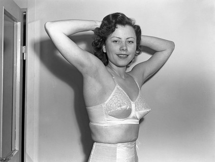 Woman of the 1940s. A young woman in a photographers studio. She holds up her arms and hands and