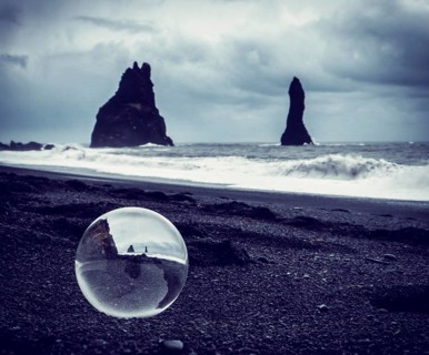 Cold sea water rolling on wet sand near rough stony cliffs on stormy day on Reynisfjara Black Beach