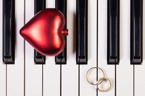 Detail of piano keyboard, red heart and wedding rings