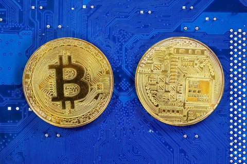 Virtual cryptocurrency money Bitcoin golden coins on a computer printed circuit board PCB. The
