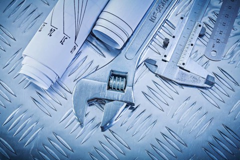 Blueprints vernier scale caliper monkey spanner on channeled metal background construction concept