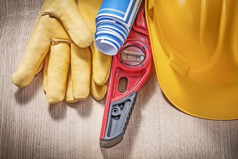 Building helmet safety gloves construction level blue blueprint rolls on wooden board