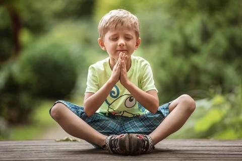 5-6 years old boy meditates in the park