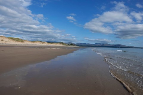 Beach and dunes with calm sea, in the background the mountains of Snowdonia National Park, Ynys