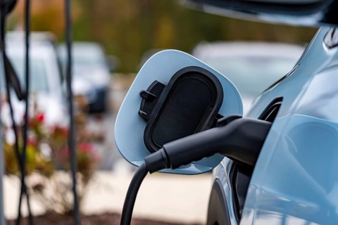 An electric vehicle recharges at a station while its owner is at work, allowing for a fully charged