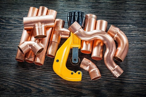 Plumbing copper water pipe cutter on wooden board