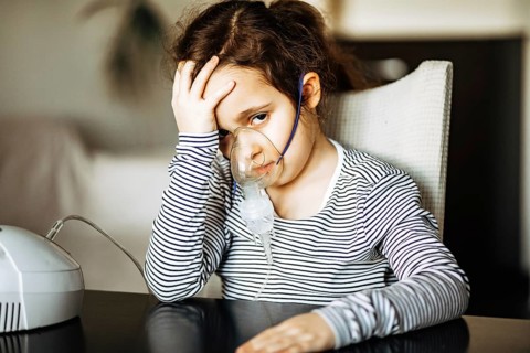 Krankes kleines Mädchen mit Husten macht Inhalation zu Hause mit Vernebler Inhalator Maske.