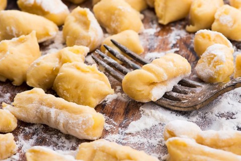 Uncooked homemade potato gnocchi with fork