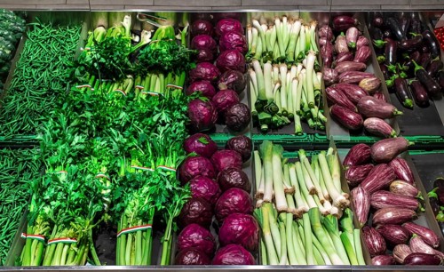 Vegetables on shelf in supermarket. Celery, eggplant, cabbage and beans