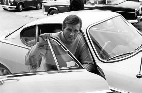 Sir Roger Moore, 1927-2017 during the filming of the tv-series The Saint, posing with a Volvo P1800