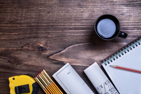 Checked copybook pencil blueprints tape line wooden meter and cup of coffee on wood board