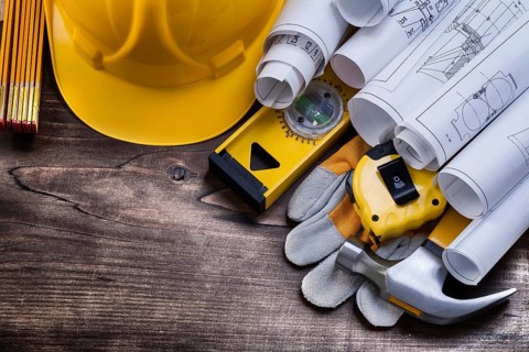 Blueprint rolls and set of construction tools on vintage pine wooden board maintenance concept