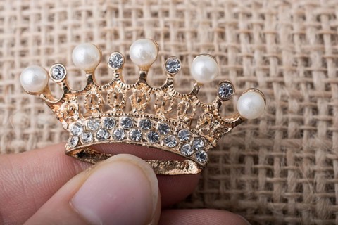 Golden color crown model with pearls on brown background