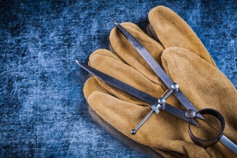 Pair of construction compasses leather protective gloves on metallic background