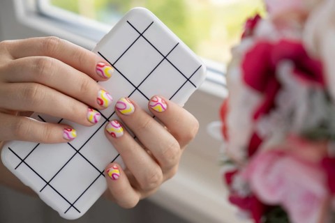 Stylish summer colorful nails female manicured hands holding mobile phone. Closeup of manicured