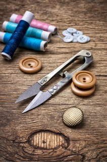 Scissors, thread and buttons on unhewn darianna background in vintage style