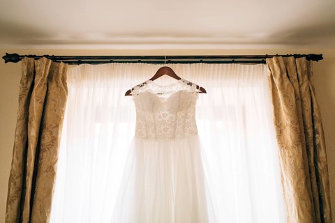 The bride's dress hangs on the cornice on the window
