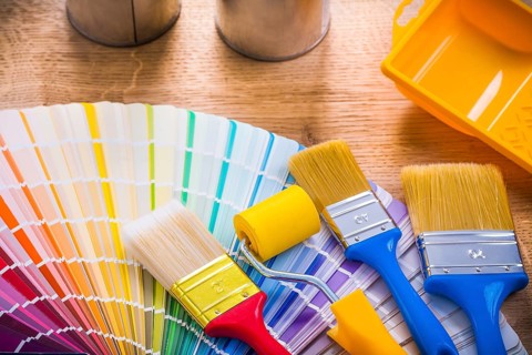 Very close up view paint brushes roller tray on wooden board