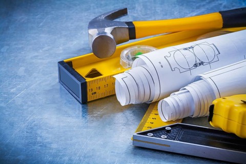 Close up image of hammer measuring line construction plans and level square ruler on metallic