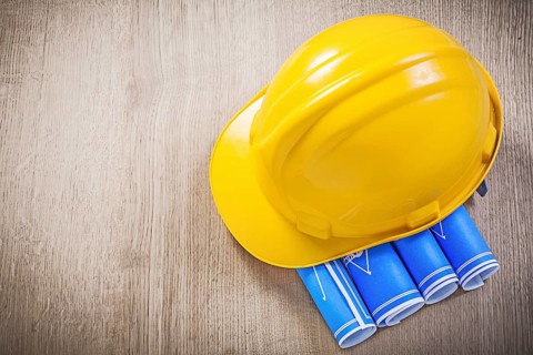 Wooden board with blue blueprints building helmet construction concept