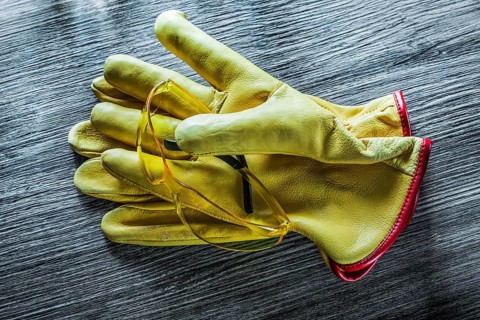 Set of safety gloves goggles on wooden board