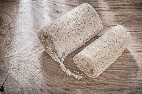 Scrubbing loofah on wooden board top view healthcare concept