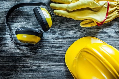 Earmuffs protective gloves hard hat on wooden board