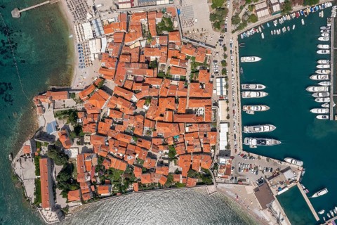 Aerial top view of walled old town of Budva city. Pier with moored yachts and boats. Adriatic sea,