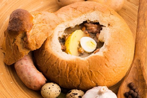Traditional white borscht (zurek) with sausage, egg and mushrooms in bread as a dish