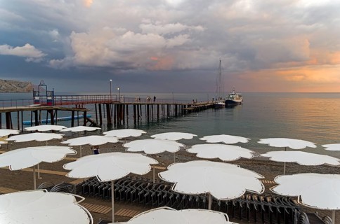 View of evening sunset sky from the empty beach of the resort town of Sudak. Crimea