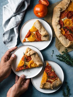 Savory fresh homemade tomato tart or galette.Hands takes piece of pie.Ideas and recipes healthy