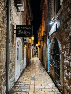 Budva, Montenegro - 25 december 2022: Signboard on a narrow street with stone houses. Caption: Old