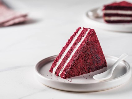 Piece of red velvet cake with perfect texture in matte plate on white marble tabletop. Slice of