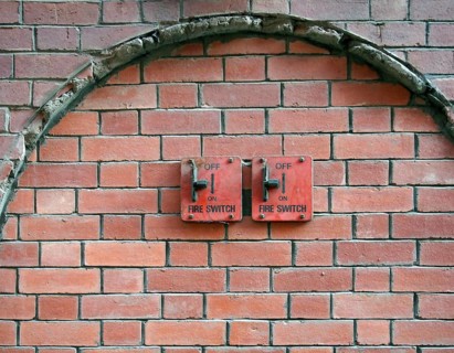 Two old red metal fire switches on an exterior brick wall