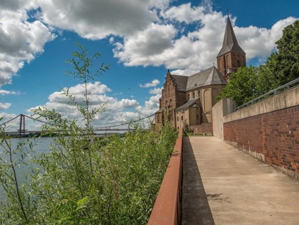 Walkway along a church, in the background a bridge and clouds in the blue sky, emmerich, lower