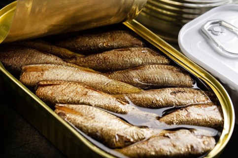 Canned smoked fish sprats in just opened tin can. Non-perishable food