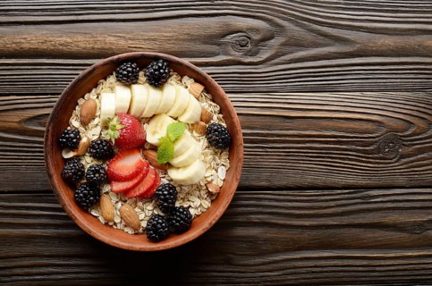Flat lay top view at Fruit healthy muesli with banana strawberry almonds and blackberry in clay