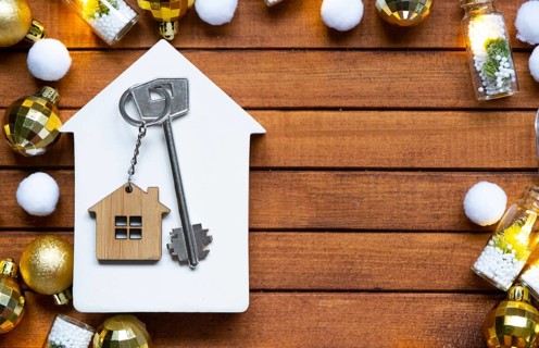 Key to house with a keychain tiny home on wooden background with Christmas decor layout. Gift for