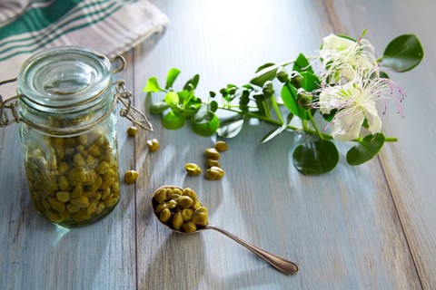 Capers pickled with plant and caper plant flower on vintage spoon