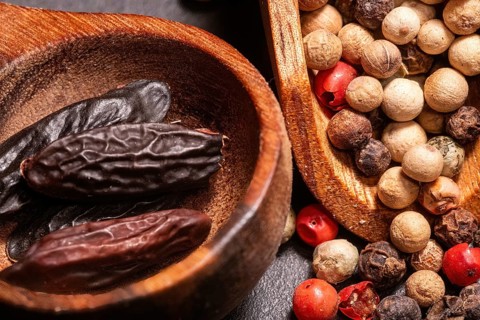 Tonka Beans and different kind of Peppercorns in a wooden spoon