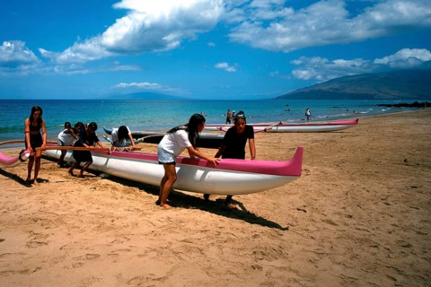 Kihei beach, an outrigger boat is pushed ashore by schoolgirls after physical education class, Maui
